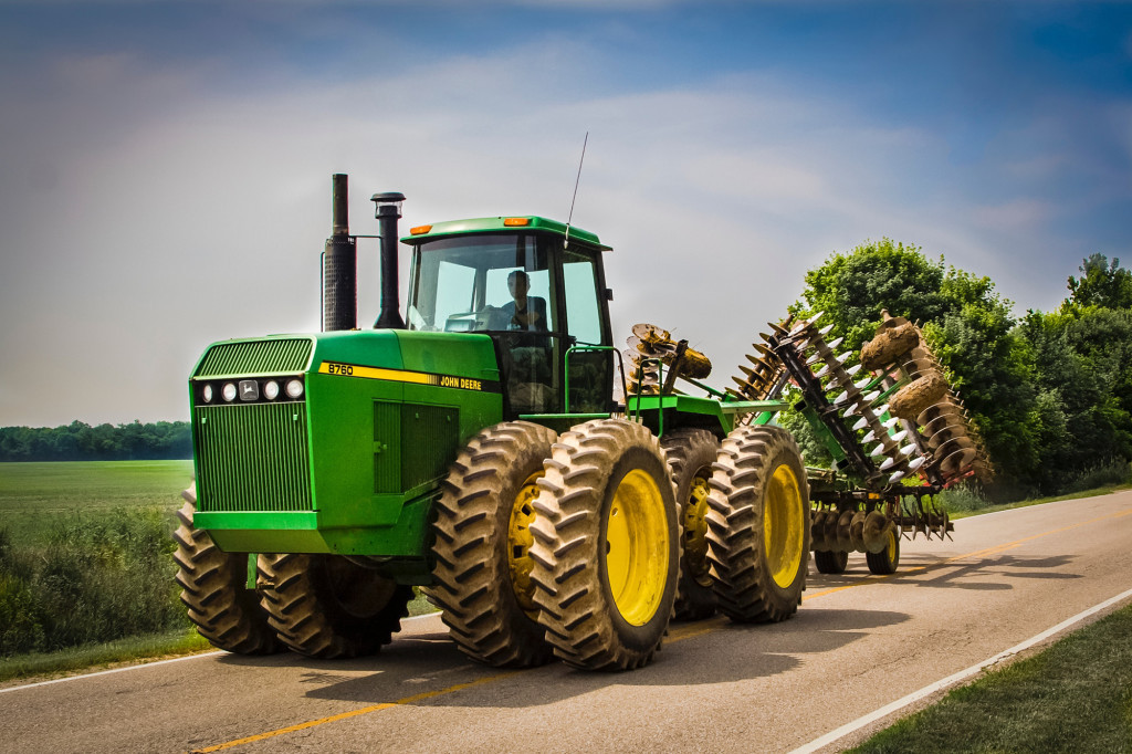 John Deere 8760 farm tractor with a folded farm tractor disc attached driving down a country road in Indiana.